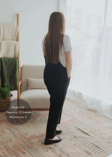 Woman in black linen/cotton Journey Overalls with deep pockets, adjustable straps, and side buttons.