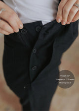 Black linen/cotton overalls with functional side buttons and deep pockets, shown on a pregnant model.