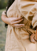 Close-up of a woman in a beige lyocell Julia Dress, showing the shirred waist and discreet nursing zipper.