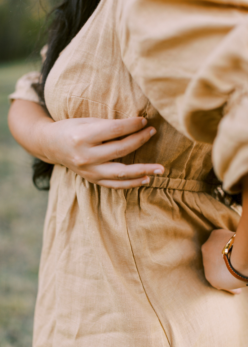 Close-up of a woman in a beige lyocell Julia Dress, showing the shirred waist and discreet nursing zipper.
