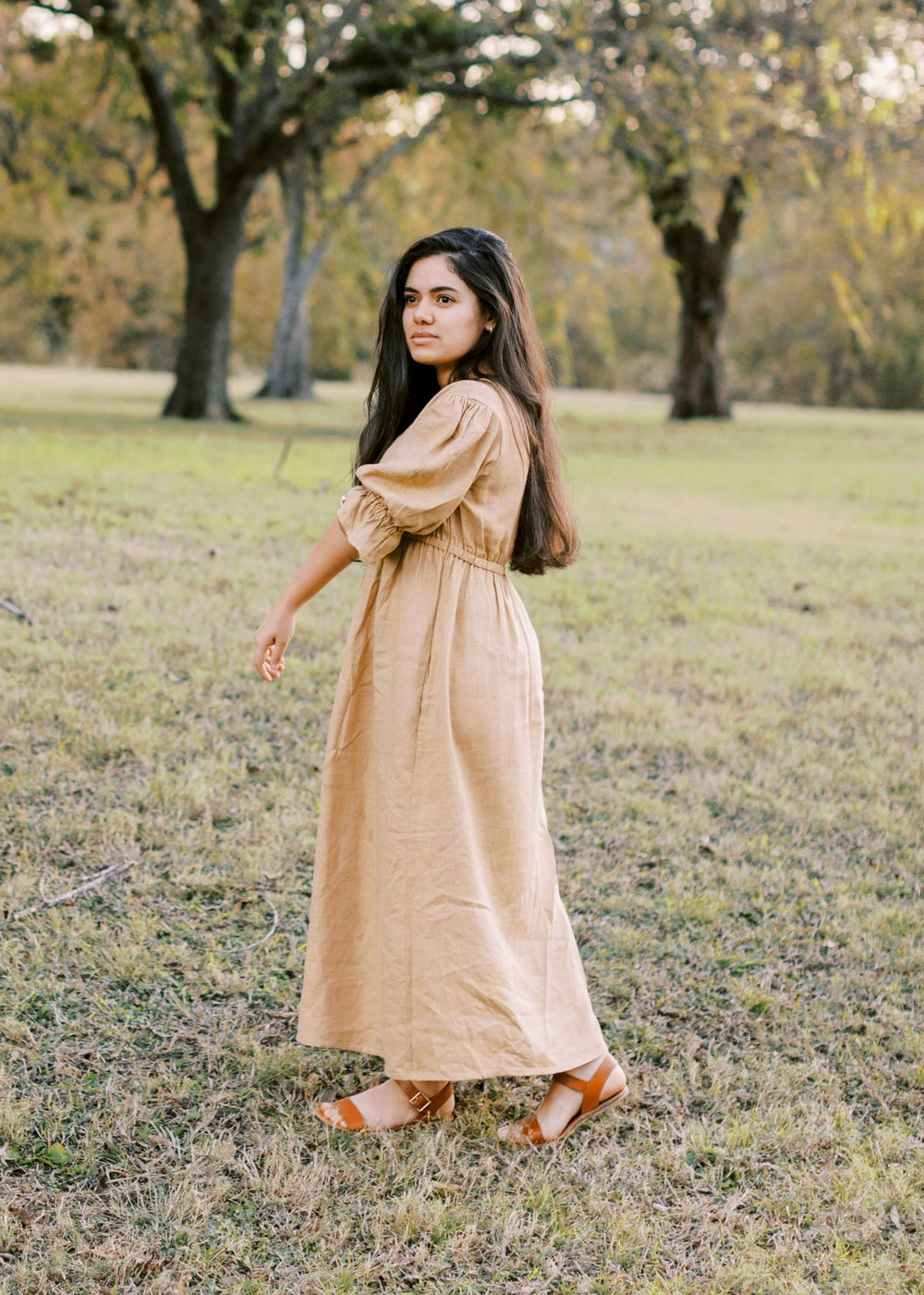 Woman in a flowing, long-sleeved beige Julia Dress made of lyocell, with a discreet nursing zipper.