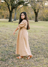 Woman in a flowing, long-sleeved beige Julia Dress made of lyocell, with a discreet nursing zipper.