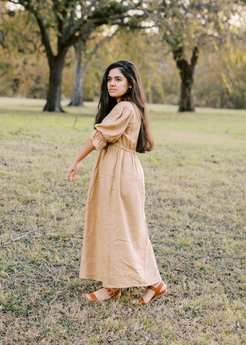 Woman in a flowing, long-sleeved beige Julia Dress made of lyocell, with a discreet nursing zipper.