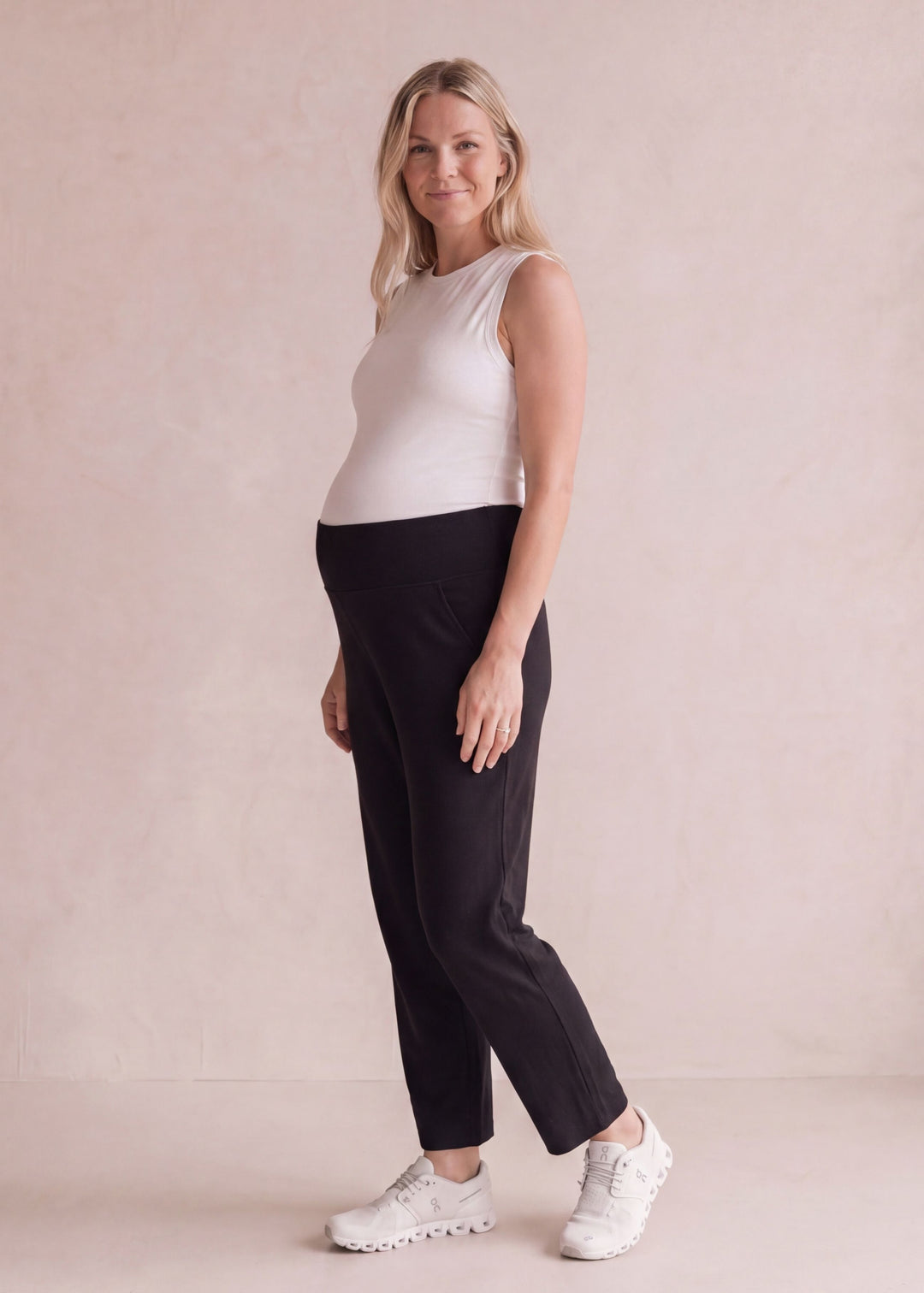 Pregnant woman in black cotton viscose knit sweater pants with a high-rise belly band.
