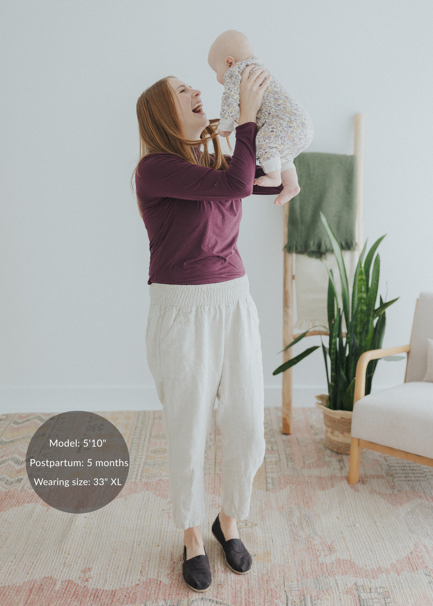 Woman holding baby, wearing Everyday Smocked Linen Pant in natural, with a flexible smocked waistband.