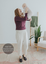 Woman holding baby, wearing Everyday Smocked Linen Pant in natural, with a flexible smocked waistband.