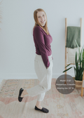 Smiling model in extended inseam natural linen smocked maternity pants and a burgundy long-sleeve top.