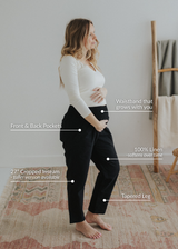 Pregnant woman in black smocked linen pants with a growing waistband, pockets, and tapered, cropped leg.
