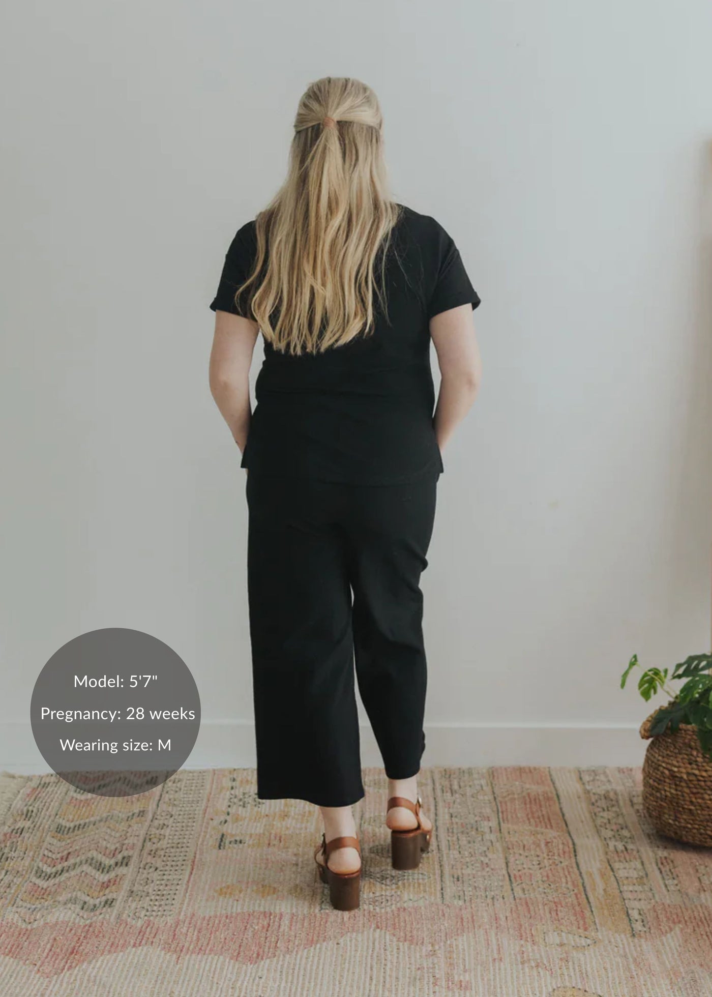 Back view of a pregnant woman in a black cotton fleece lounge set with a relaxed fit.