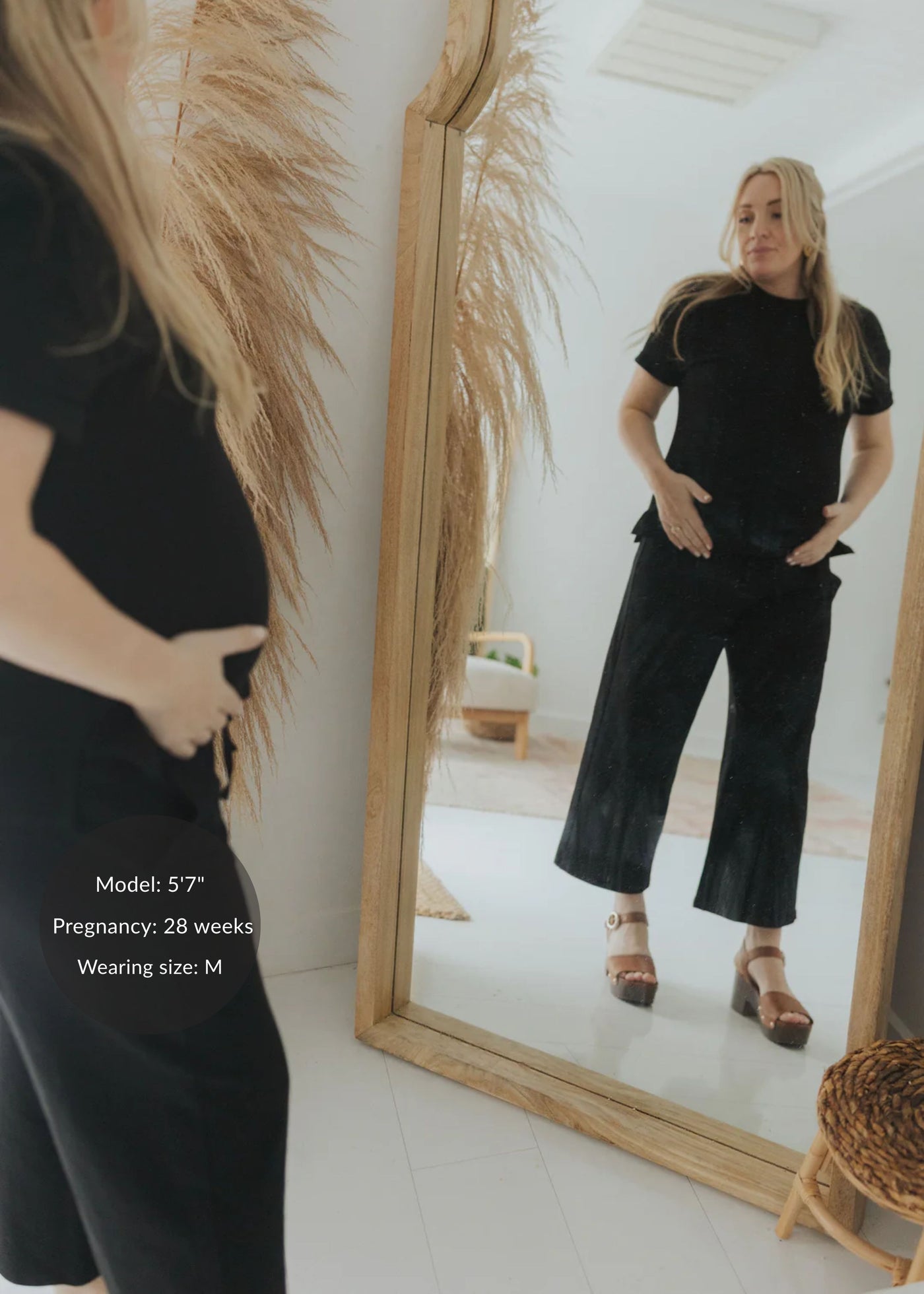 Pregnant woman in a black cotton fleece lounge set, featuring a relaxed top and wide-leg pants.