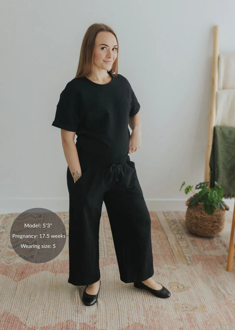 Pregnant woman in a black cotton fleece lounge set with wide-leg pants and a relaxed-fit top.