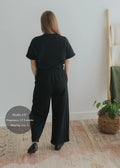 Woman from behind wearing a black cotton fleece lounge set with a relaxed top and wide-leg pants.