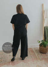 Woman from behind wearing a black cotton fleece lounge set with a relaxed top and wide-leg pants.