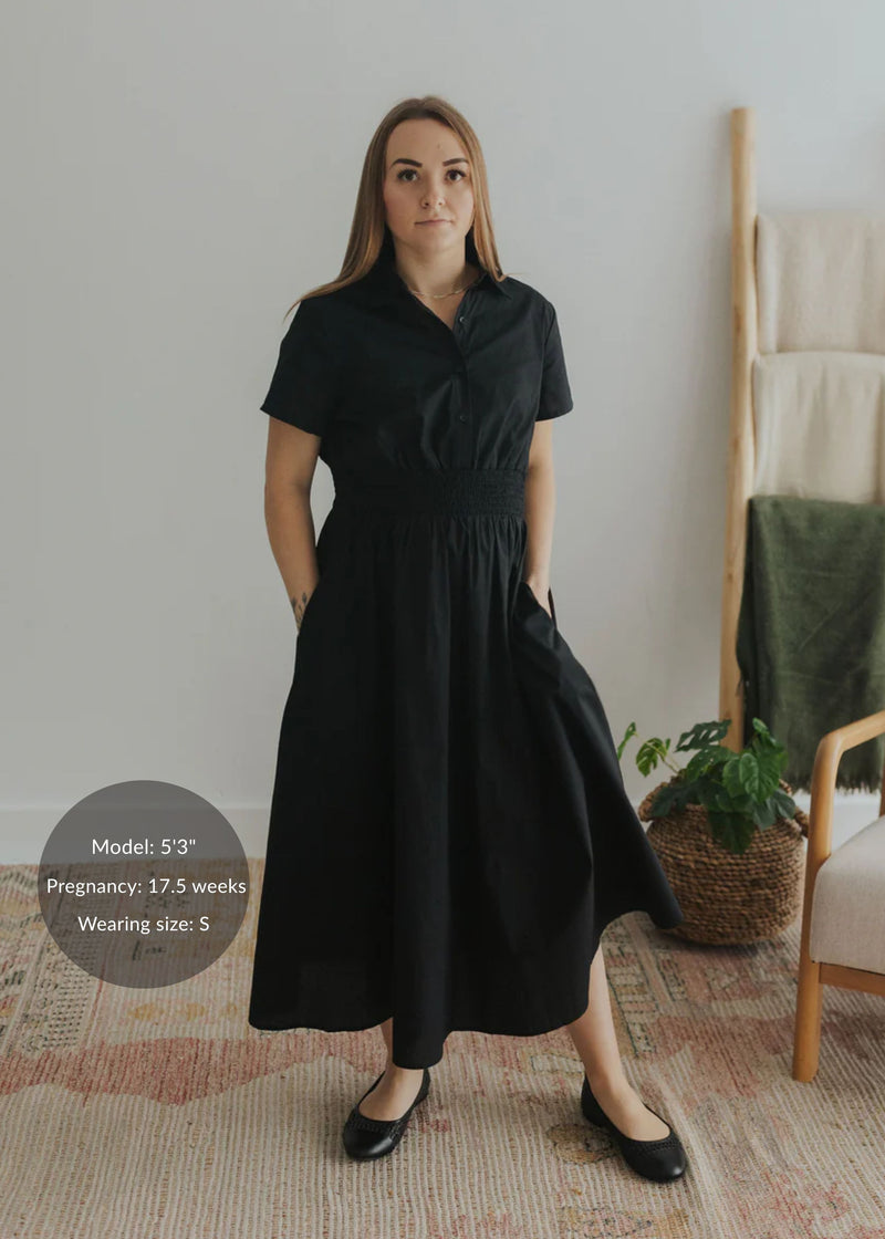 Woman in black cotton poplin Sarah Shirt Dress with short sleeves, button front, and smocked waist.