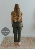 Back view of a pregnant model wearing olive green smocked linen pants with functional pockets.