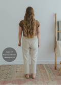 Back view of a pregnant model wearing natural linen smocked waist pants with pockets.