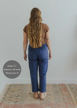 Model from behind wearing blue smocked linen maternity pants with a brown top.