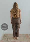 Model from behind wearing brown smocked linen maternity pants with pockets.