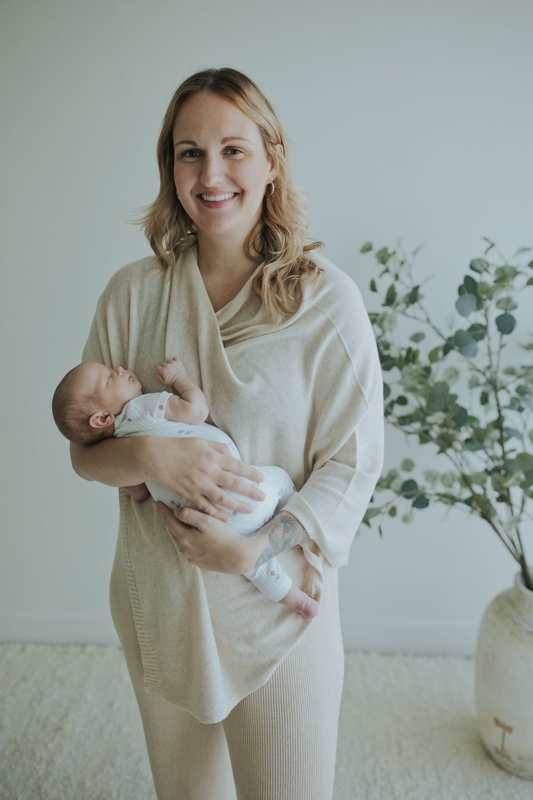 Smiling mother holding her newborn in the Oatmeal Nursing Cover in Cotton Cashmere