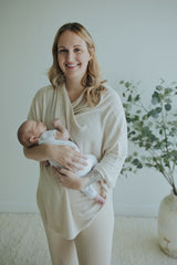 Smiling mother holding her newborn in the Oatmeal Nursing Cover in Cotton Cashmere