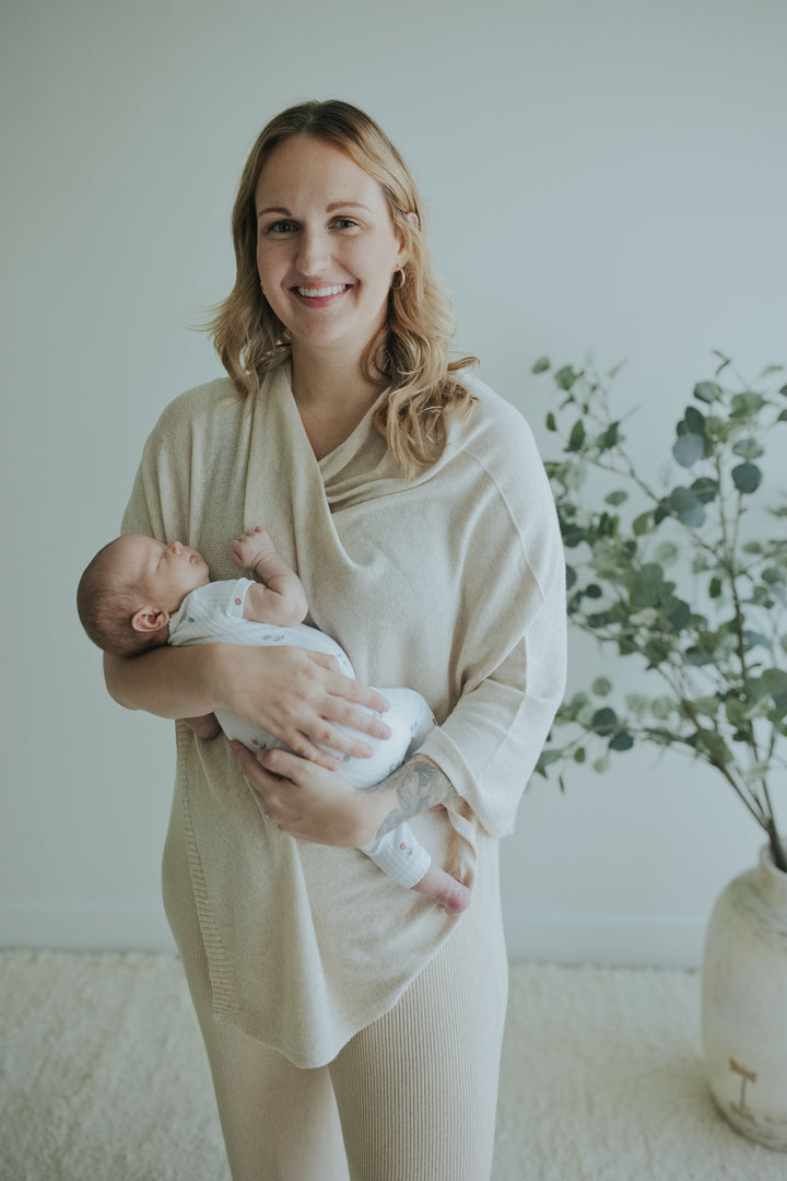 Smiling mother holding her newborn in the Oatmeal Nursing Cover in Cotton Cashmere