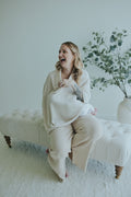 Laughing mother seated in the Oatmeal Nursing Cover