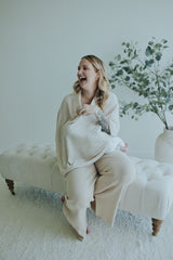 Laughing mother seated in the Oatmeal Nursing Cover