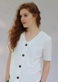 White linen-cotton Olivia Button Down Top with V-neckline and dark brown buttons on a woman with red hair.