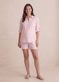 Smiling woman in an oversized pink linen co-ord with a button-up shirt and shorts.