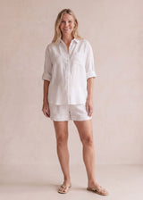 Woman in a white oversized linen co-ord set with a button-down shirt and shorts, perfect for comfort.