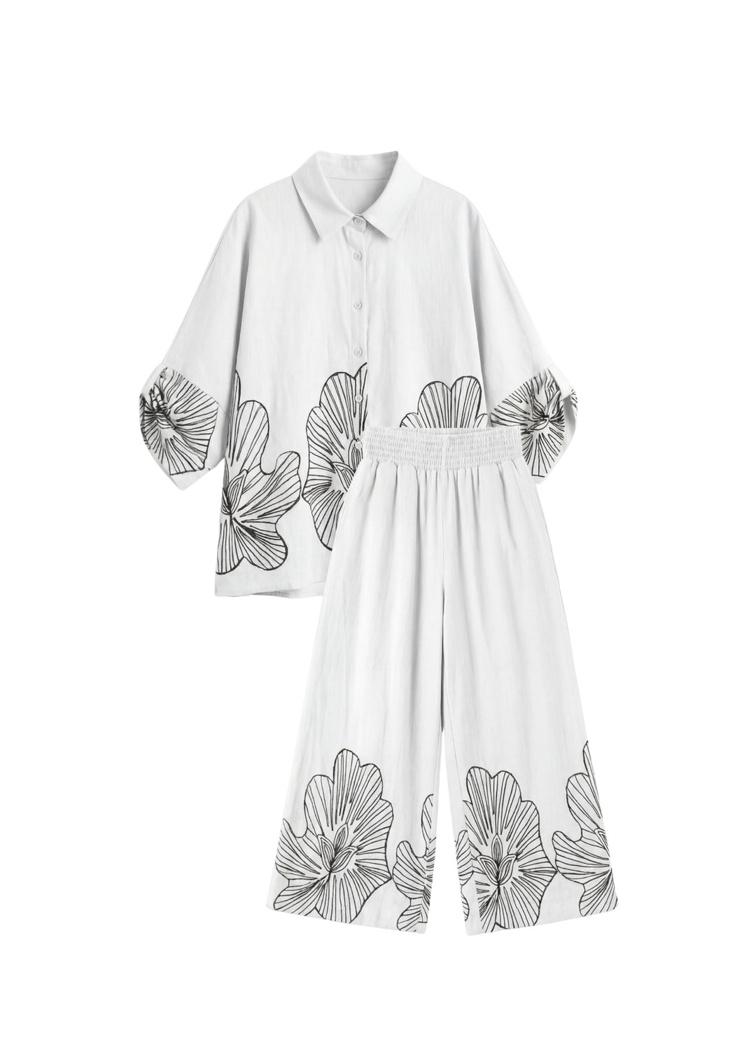 White oversized cotton smocked set with black floral print, featuring a loose shirt and wide-leg pants.