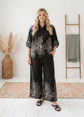 Model wearing the Oversized Floral Print Smocked Set in Black — relaxed two-piece maternity set
