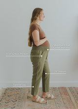 Pregnant woman in profile wearing olive garment-washed linen/cotton smocked pants with pockets and tapered leg.