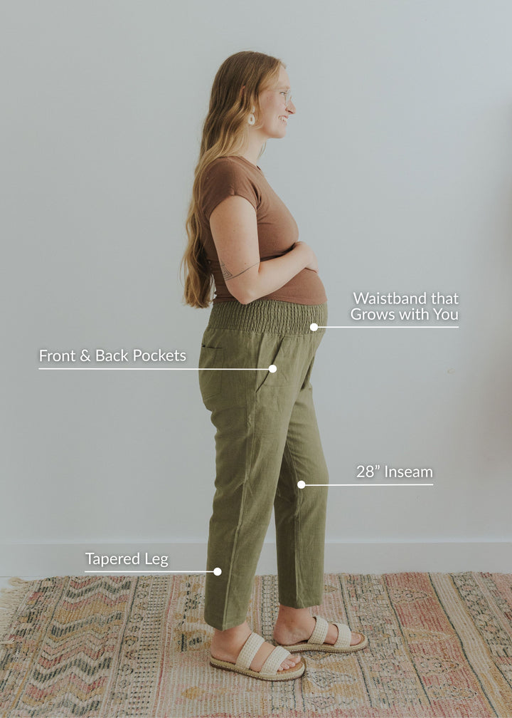 Pregnant woman in profile wearing olive garment-washed linen/cotton smocked pants with pockets and tapered leg.