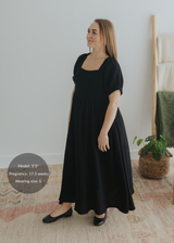 Black cotton gauze maxi dress with square neck, smocked bodice, puffed sleeves, and tiered skirt.