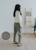 Pregnant woman in olive green straight leg cotton/linen trousers and a cream ribbed top.