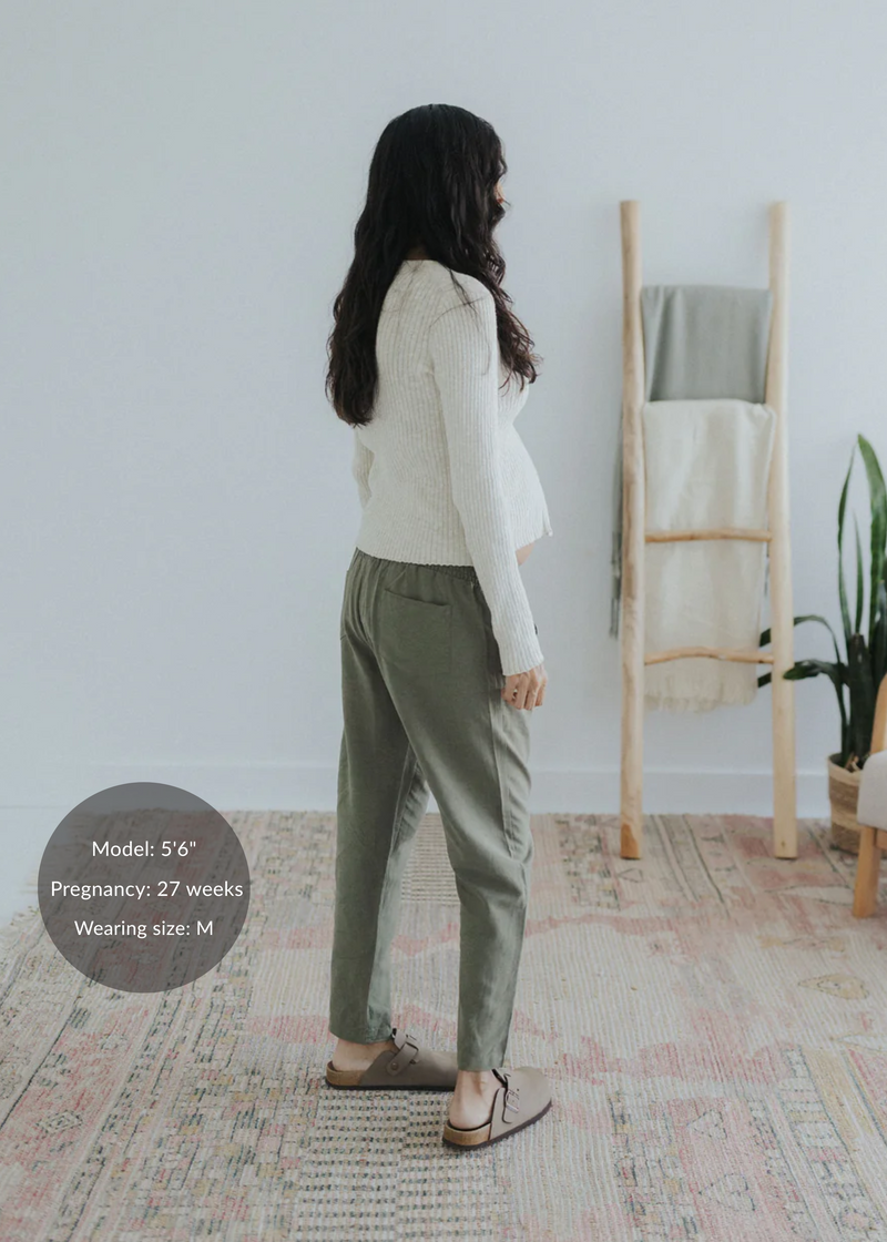 Pregnant woman in olive green straight leg cotton/linen trousers and a cream ribbed top.