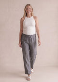 Smiling woman in gray tapered drawstring sweatpants and a white tank top.