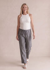 Smiling woman in gray tapered drawstring sweatpants and a white tank top.