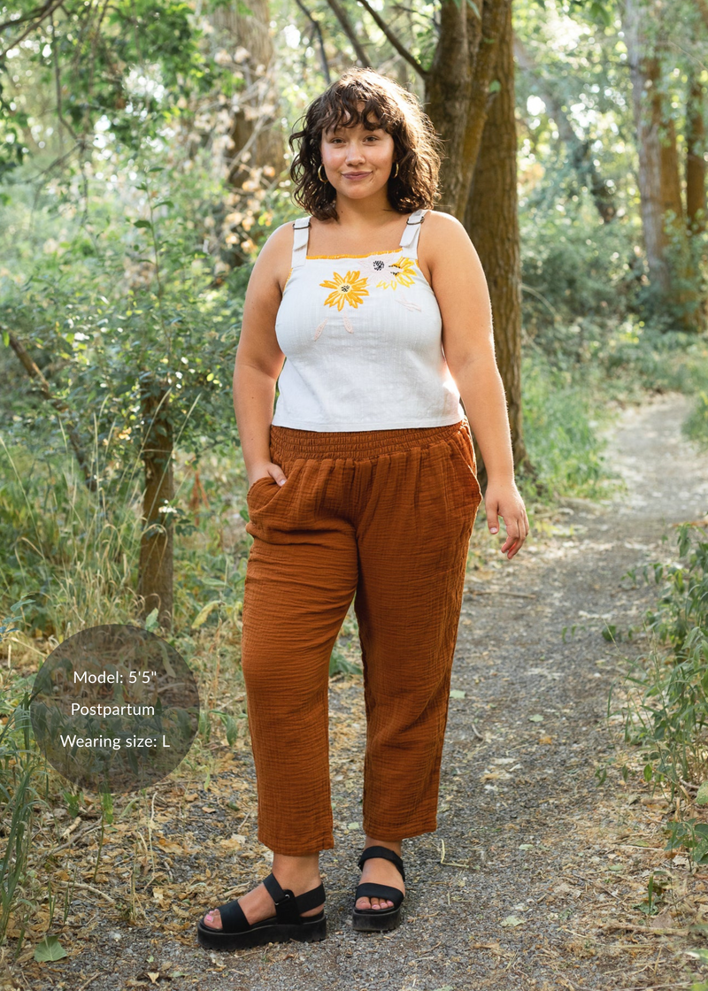 Woman in Everyday Breeze Pant in rust cotton gauze with elastic waistband and pockets.