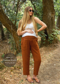 Pregnant woman in rust cotton gauze Everyday Breeze Pant with elastic waist, deep pockets, and white top.