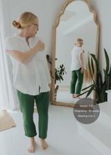 Woman in a white cotton gauze shirt and green Everyday Breeze Pant, reflected in a mirror.