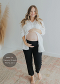Pregnant woman in black cotton gauze Everyday Breeze Pant and white shirt, holding her belly.
