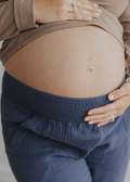 Pregnant belly wearing Everyday Breeze Pant in blue cotton gauze with elastic waistband.