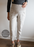 Pregnant model wearing natural linen smocked maternity pants with pockets and rolled cuffs.