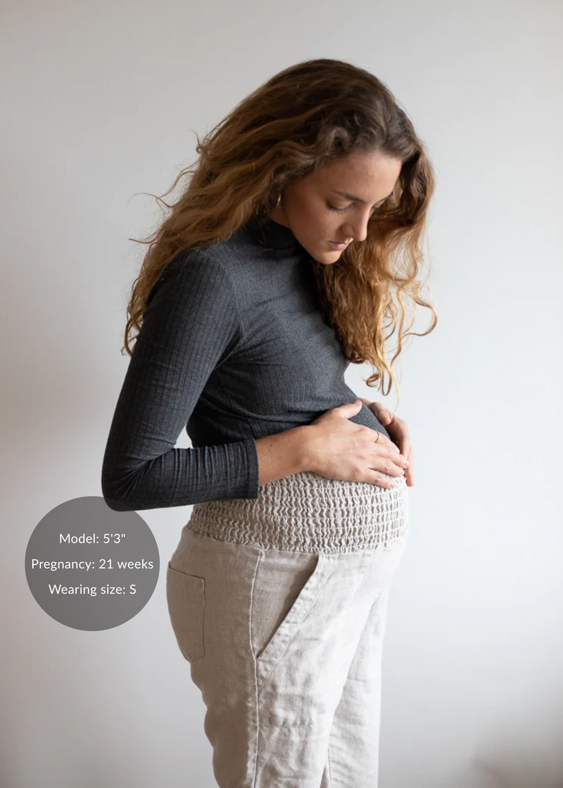 Pregnant model wearing Everyday Transitional Smocked Linen Pants in natural, with a comfortable smocked waistband and pockets.