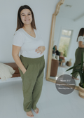 Pregnant model in olive green smocked linen pants with pockets and a white tee.
