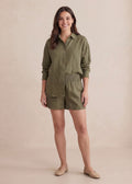 Smiling woman in a relaxed-fit olive green cotton gauze shirt and matching smocked-waist shorts.