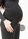 Maternity model in black linen smocked-waist pants, extended inseam, supporting a 28-week baby bump.