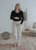 Smiling pregnant woman in natural linen smocked maternity pants with extended inseam and black top.